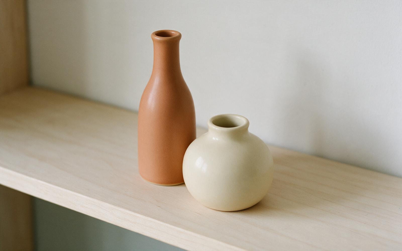 A tall and a short vase grouped together on a shelf